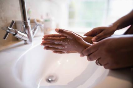 Adult helping child wash hands