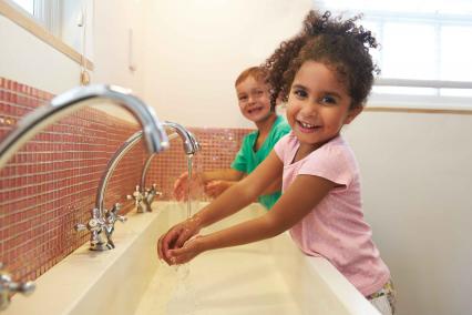 Kids washing hands in a school bathroom